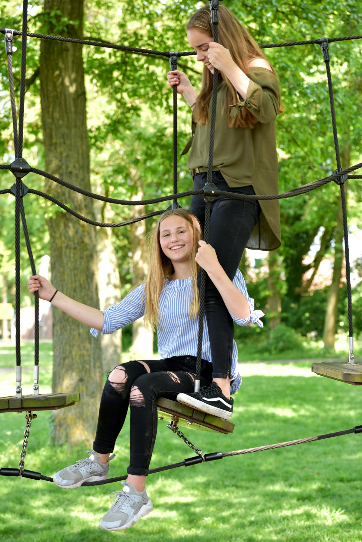 Twee meiden klimmen samen in een klimnet in het park