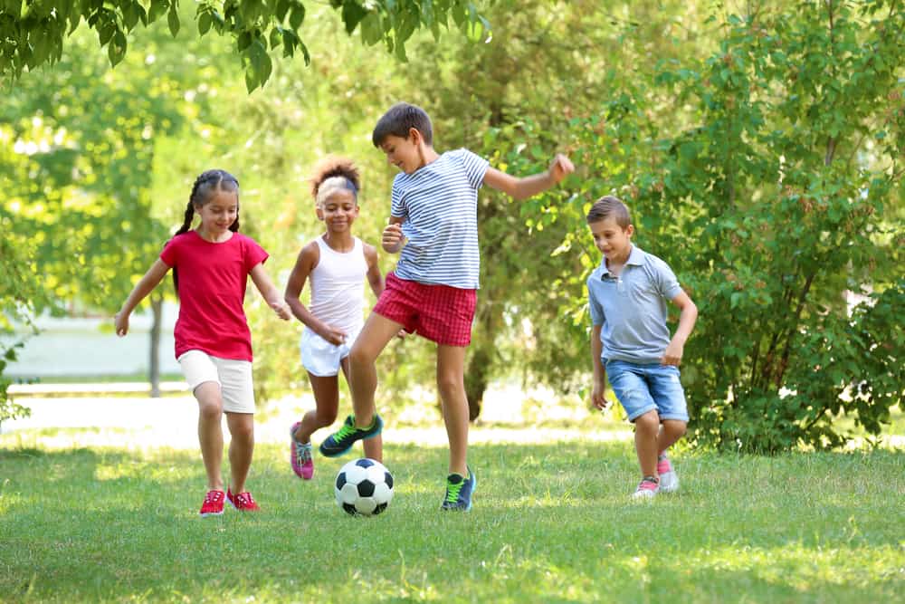 Vier kinderen voetballen samen in het park
